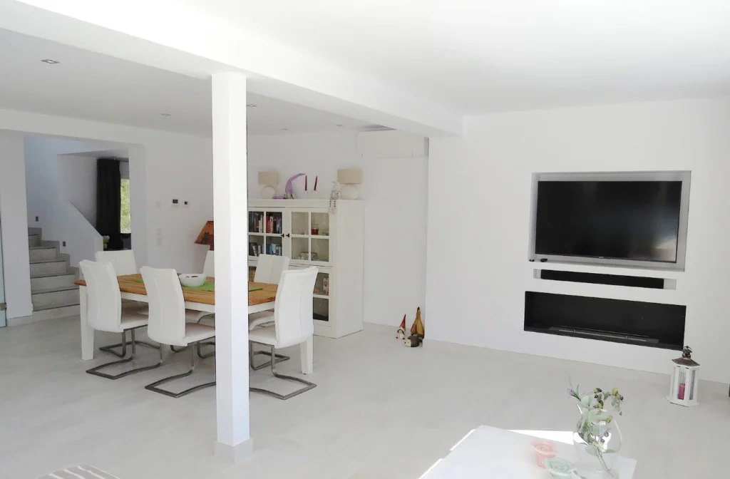 Helles Esszimmer der Villa Oliva mit Teil vom Wohnzimmer mit Kamin